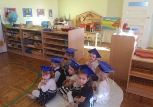 Dzieci siedzą na dywaniku.