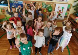 Dzieci machają pozując do zdjęcia.