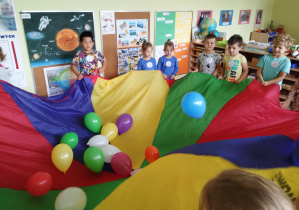 Dzieci bawią się chustą animacyjną i balonami.