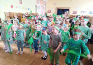 Dzieci tańczą z zielonymi wstążeczkami.