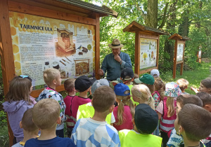 Dzieci omawiają z pszczelarzem zawartość tablic edukacyjnych.