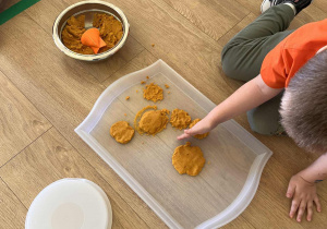 Dziecko pracuje z masą sensoryczną wykonaną na bazie dyni.