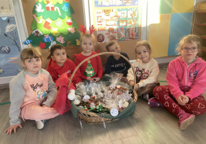 Zdjęcie dzieci z koszem własnoręcznie przygotowanych upominków. Zdjęcie wykonane w sali przedszkolnej.
