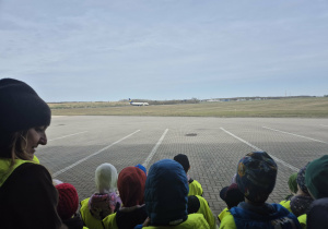 Dzieci obserwują lądujący samolot.