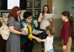 Pani prezydent wręcza podziękowanie dla dziewczynki, której praca jest częścią wystawy.