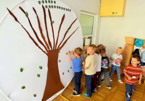 Dzieci przypinają listki do drzewa życzliwości. Jeden listek to jeden dobry uczynek.