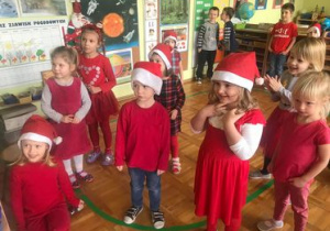 Dzieci ubrane na czerwono cieszą się z wizyty Mikołaja.