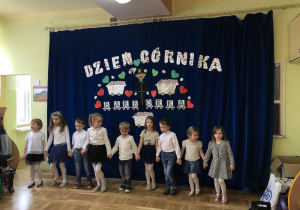Dzieci stoją na tle dekoracji z okazji Dnia Górnika.