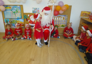 Mikołaj siedzi wśród dzieci.