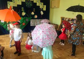 Dzieci tańczą z parasolami.
