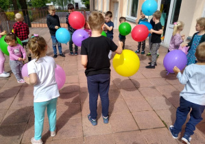 Dzieci na tarasie bawią się balonami.