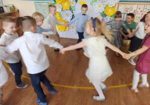 Dzieci tańczą trzymając się za ręce.